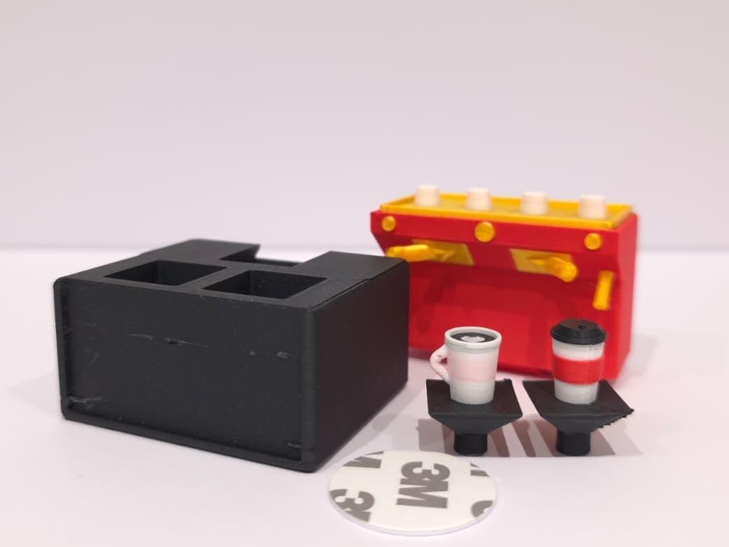 The espresso shop in pieces: the black base, the machine, the two cups on their keys and the round NFC sticker