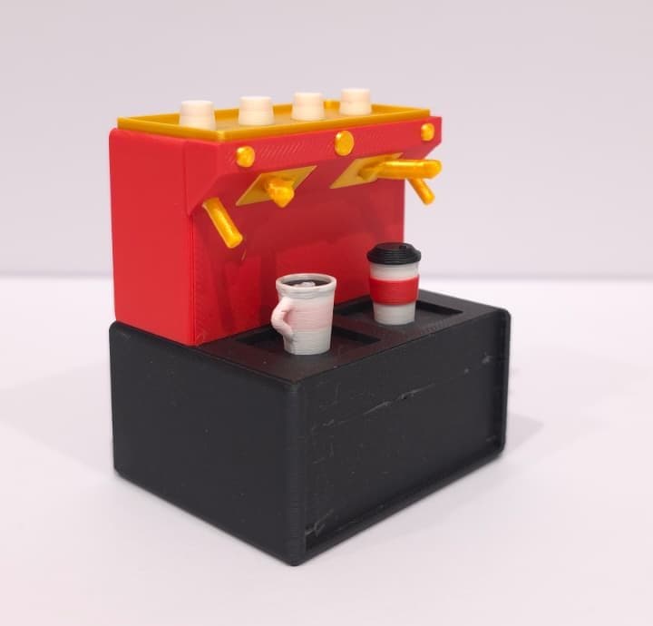 The printed espresso shop: a red machine with gold trim on a black base, a mug and a takeaway cup in front