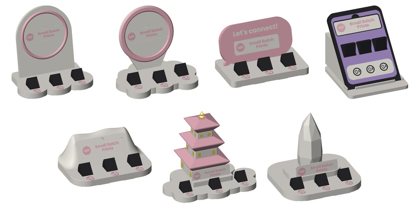 Seven Small Batch Prints counter stands in ivory and pink: an arch, a halo ring, a speech bubble, a phone, a wave, a pagoda and a monolith, each with three icon tiles along the front
